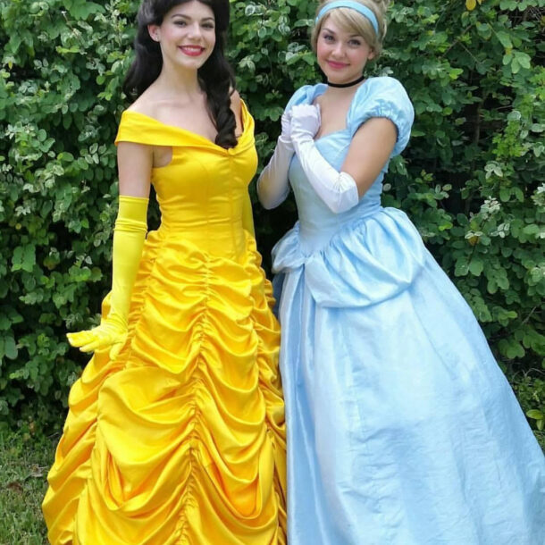 Two women dressed as Disney princesses in bright yellow and blue gowns.